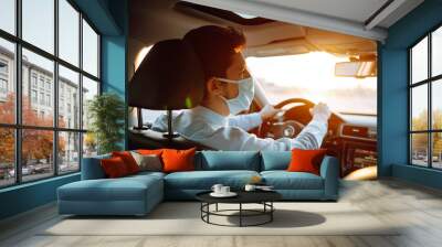 Young man  in protective sterile medical mask sits in the car during an epidemic in quarantine city. Health protection, safety and pandemic concept. Covid - 19. Wall mural