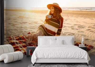 Young woman drinking morning coffee at picnic on the beach. Rest, relaxation, travel, lifestyle concept. Wall mural