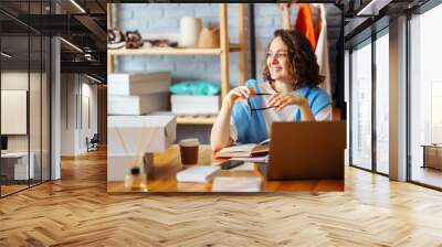 young woman takes notes of orders from with laptop. dropshipping business owner working in her offic Wall mural