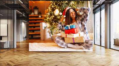 Young woman with christmas presents by the christmas tree. Winter holidays. Wall mural