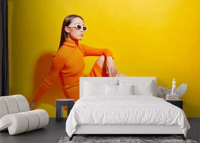 Fashion asian female model. Orange dress, white boots, sunglasses. Wall mural