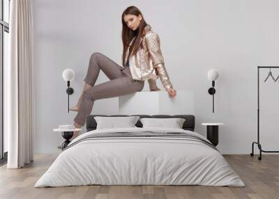 Fashion model in golden leather jacket posing in studio. Wall mural