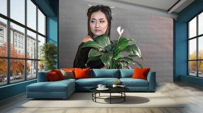 a girl of oriental appearance on a gray background with a green flower in her hands Wall mural