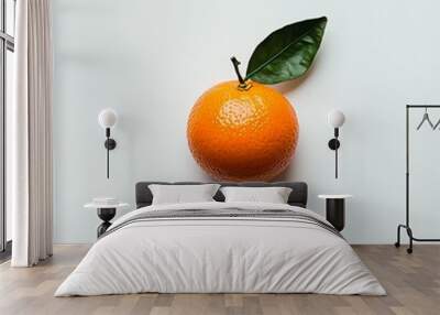 An orange fruit with a green leaf on a white background is pictured in detail Wall mural