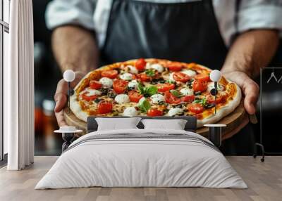 In a restaurant kitchen, a chef serves a hot Margherita pizza garnished with basil, tomato, and mozzarella. Wall mural