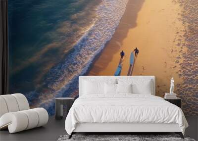 On a sandy beach, two surfers walk with longboards and carry them Wall mural