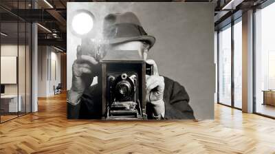 1940's 1930's style portrait of photojournalist. Headshot : Man looking and holding a vintage camera with magnesium flash. Black, White shot of a retro 1940's photographer wearing a Fedora hat Wall mural