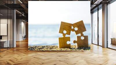 four 4 wooden puzzles standing on sand beach on on blue sea and sky background. family on resort idea. Wall mural