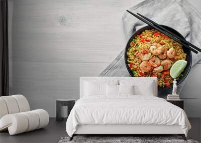 Shrimp fried rice with vegetables, green onions and lime in a black pottery bowl. Traditional Thai meal on a white table with fabric tablecloth. Top view, directly above shot with space for text. Wall mural