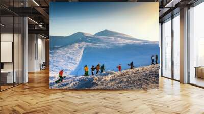 Young people in a mountain are ready to ride on snowboards. Group of snowboarders in Carpathian mountains. Wall mural