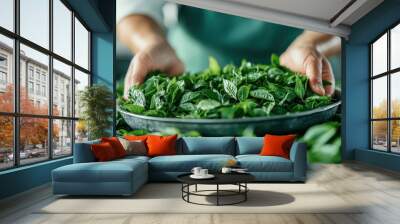 A close-up image of hands holding a tray full of fresh green leaves, likely in a kitchen or food preparation area, highlighting freshness and organic produce. Wall mural