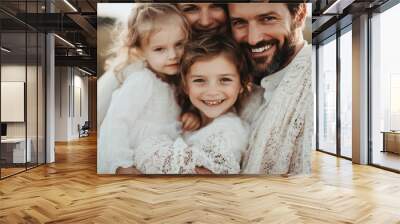 A loving family of four, with parents and two children, smile warmly while wrapped in cozy blankets, radiating happiness, unity, and affection in an outdoor setting. Wall mural