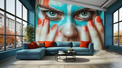 A striking close-up image of a person's face adorned in bold, vibrant colored face paint, showcasing artistic expression and intense focus. Wall mural