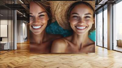 A vibrant image of two women wearing straw hats, posing closely with bright smiles. They both radiate happiness and joy, basking by the pool on a sunny day. Wall mural