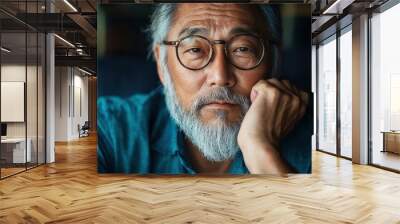 An elderly Asian man with a full beard, wearing round glasses, is captured in a relaxed pose. His serene expression and casual clothing exude comfort and ease. Wall mural