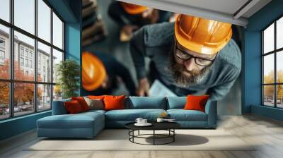 Image capturing workers collaborating in an industrial setting with safety gear, highlighting teamwork, safety protocols, and a productive work environment. Wall mural