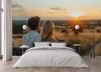 A couple is sitting in a jeep on a grassy field, watching the sun set. Scene is romantic and peaceful Wall mural