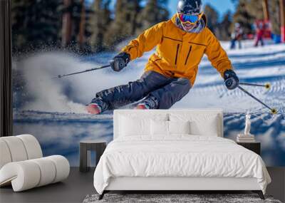 A man in a yellow jacket is skiing down a snowy slope. He is wearing goggles and a helmet for safety Wall mural