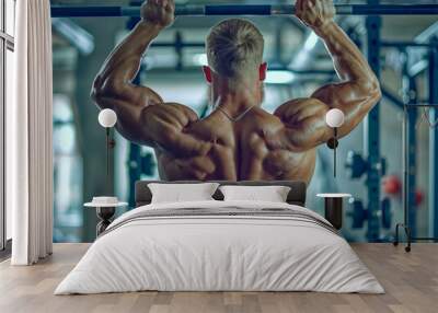 A man is lifting weights in a gym. He has a muscular back and is wearing a necklace Wall mural