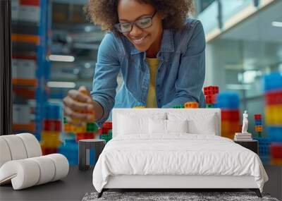 A woman is playing with a large pile of colorful blocks. She is smiling and she is enjoying herself. The blocks are arranged in various shapes and sizes, creating a fun and playful atmosphere Wall mural