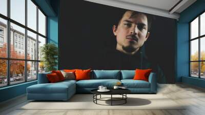 Portrait of young man on the black background Wall mural