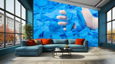 Hand in new white latex medical glove on background of a lot blue rubber gloves Wall mural