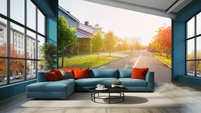 Street in residential area in suburb on sunset. Rows of houses along road. Family house outside city. Dream country home. Home outside the city. Road at village. Trees and green lawn at Villa. Wall mural