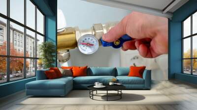 The plumber hand connects the thermometer to the supply pipe of collector for the warm floor.  Automatic water supply system, hands turn off the main valve Wall mural