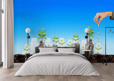 hand putting a coin in jar, saving money Wall mural