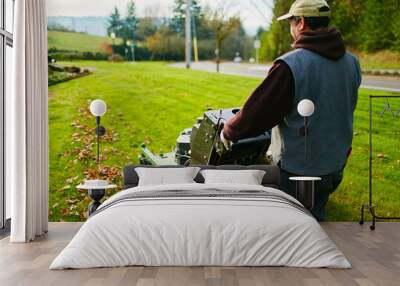 man mowing a lawn in the morning with leaves Wall mural