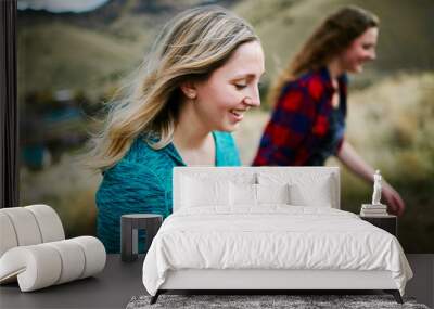 two young women hiking up a hill smiling Wall mural