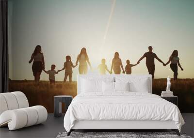 community large family in the park. a large group of people holding hands walking silhouette on nature sunset in the park. big lifestyle family kid dream concept. people in the park. large family Wall mural