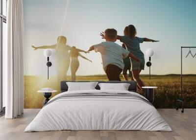 kids run in the park at sunset. friendly family children camp kid dream concept. a group of children run on the grass at the rays fun of the sun silhouette. childhood dream teamwork sunset concept Wall mural