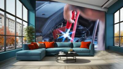 A jump start, act of using a charged battery with a new one or another car with a big pair of battery jumper cable, safely jump start a dead battery concept. Wall mural