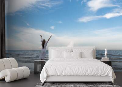 Happy young woman raised hands up on the beach with happily on blue sky and sea, time to traveling concept. Wall mural