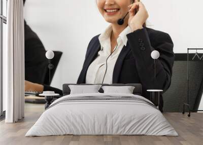 Young Asian woman in business customer service department with phone call headset on white background.
 Wall mural