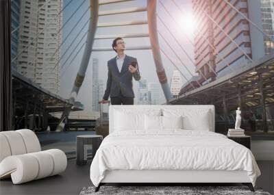 Young Businessman hand carrying travel suitcase and using mobile phone application for finding directions and looking up, future job, hope, direction,  way and  opportunity concepts. Wall mural