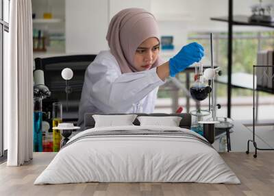 Young Muslim woman doing research in laboratory. Wall mural