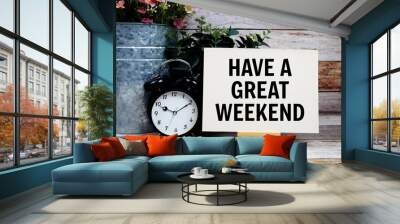 Have a great weekend text on paper card and easel standing with alarm clock on wooden background Wall mural