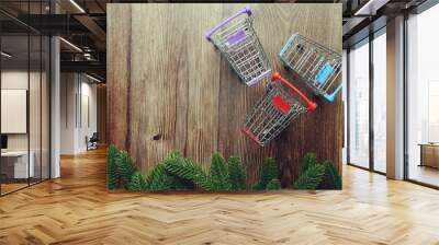 Mini Shopping Trolley  with fir tree branches border frame on wooden background
 Wall mural