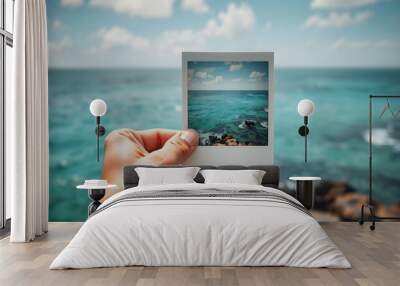 A person holding up a Polaroid picture in front of the ocean, perfect for travel or vacation themes isolated with white shades, png Wall mural