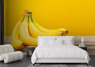 bunch of bananas on  wooden table on yellow background Wall mural