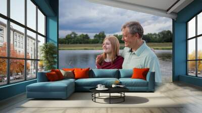 father and teenage daughter relaxing together outdoors in summer Wall mural