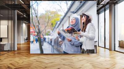 Travel, muslim, Two Asian female tourists of different religions friends visitor learning about history of fushimi inari shrine in travel book while walking through senbon torii path in Kyoto Japan. Wall mural