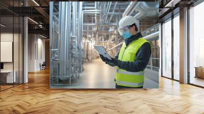 Industrial worker with a face mask and goggles, inspecting equipment in an empty factory hall Wall mural