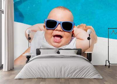 A baby boy has fun with his mother at the blue pool Wall mural