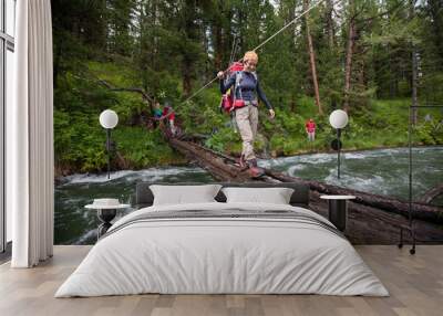 Backpackers are crossing mountain river by wooden log in Altai m Wall mural