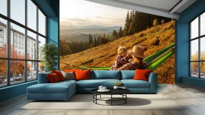 Boy tourist resting in a hammock in the mountains at sunset Wall mural