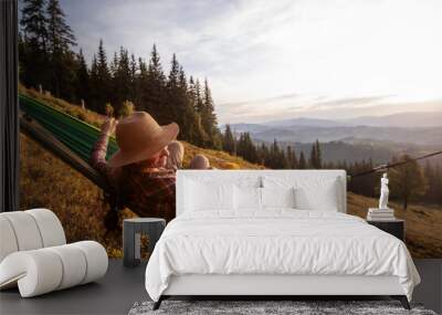 Boy with mom resting in a hammock in the mountains at sunset Wall mural