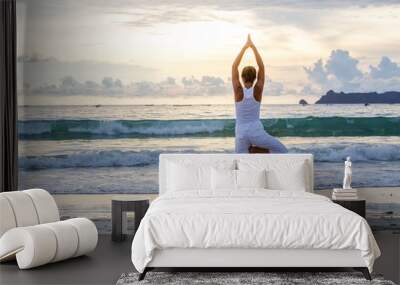 Caucasian woman practicing yoga at seashore of tropic ocean Wall mural